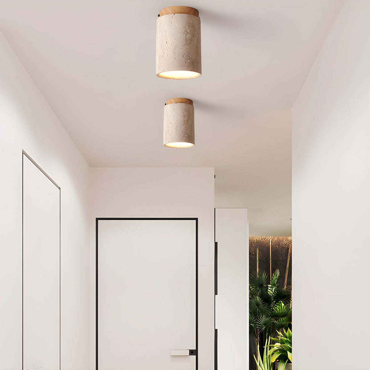A pair of Clérachic travertine ceiling lights with wood-colour caps, lit one behind the other along a bright white corridor.