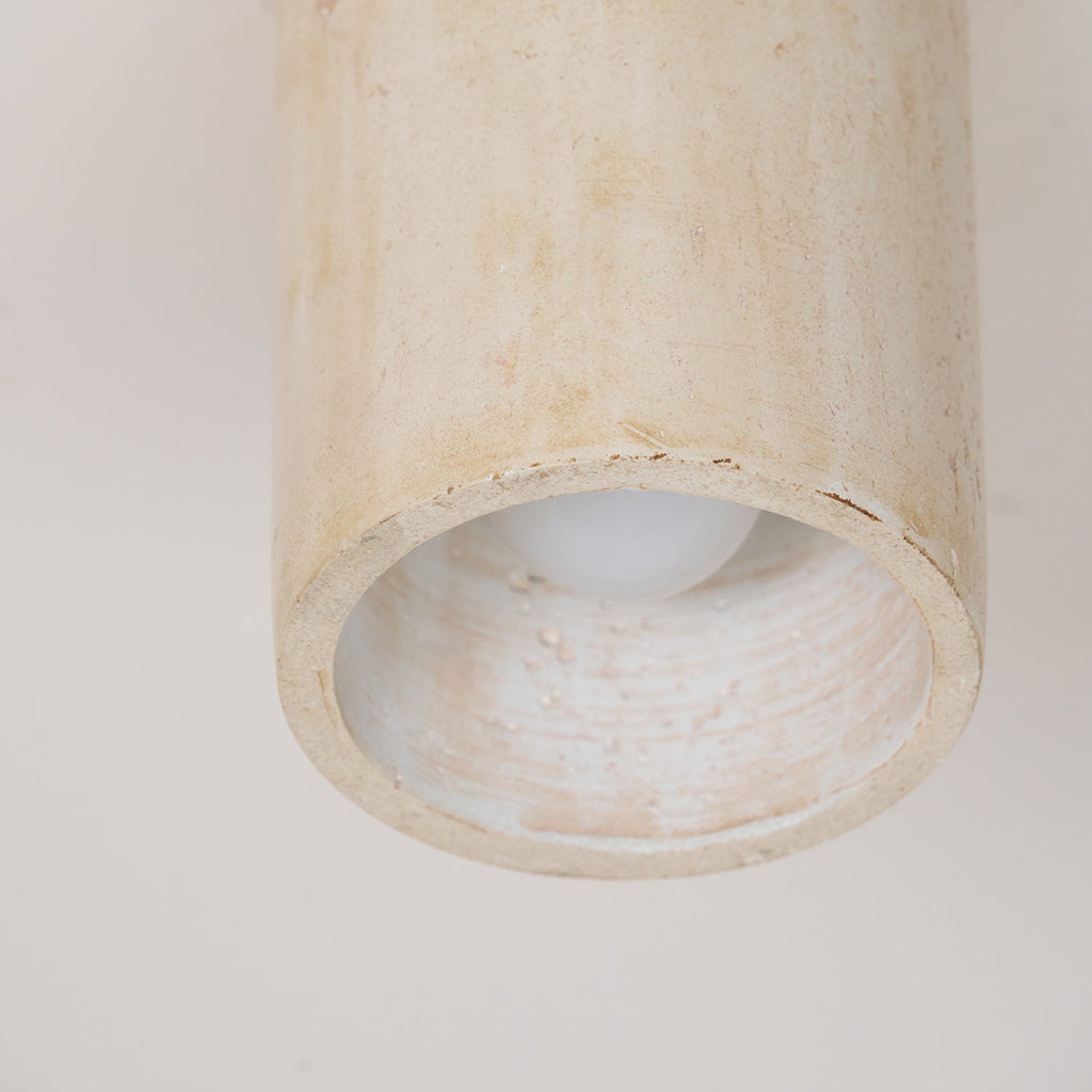 Looking up into the open end of this Clérachic ceiling light, the bulb and the ridged stone interior visible inside the rim.