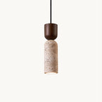 Clérachic travertine pendant on a plain off-white backdrop, a walnut-coloured cap above a pitted beige stone cylinder, lit at the base.