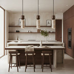 A row of three Clérachic stone pendants above a pale kitchen island, with walnut stools and open wooden shelves beyond.