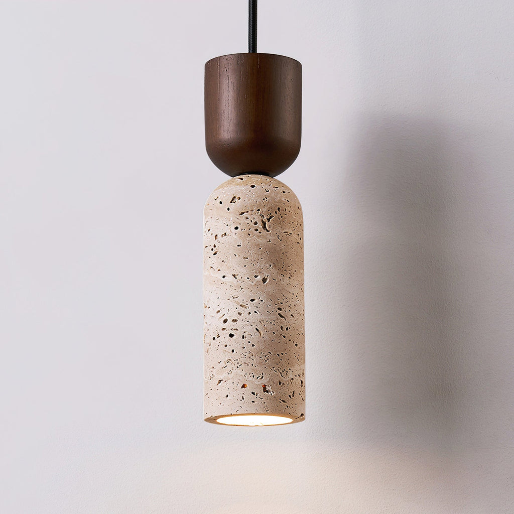 Close three-quarter view of a Clérachic pendant, its walnut cap and pitted beige travertine cylinder against a soft grey wall.