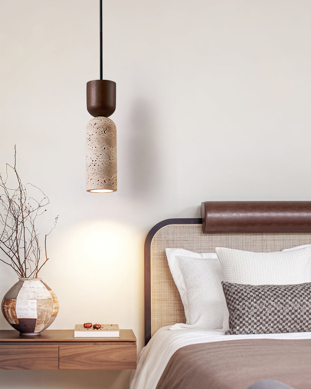 Clérachic pendant with a walnut cap and stone body hanging by a bed with a rattan headboard and a round vase on the nightstand.