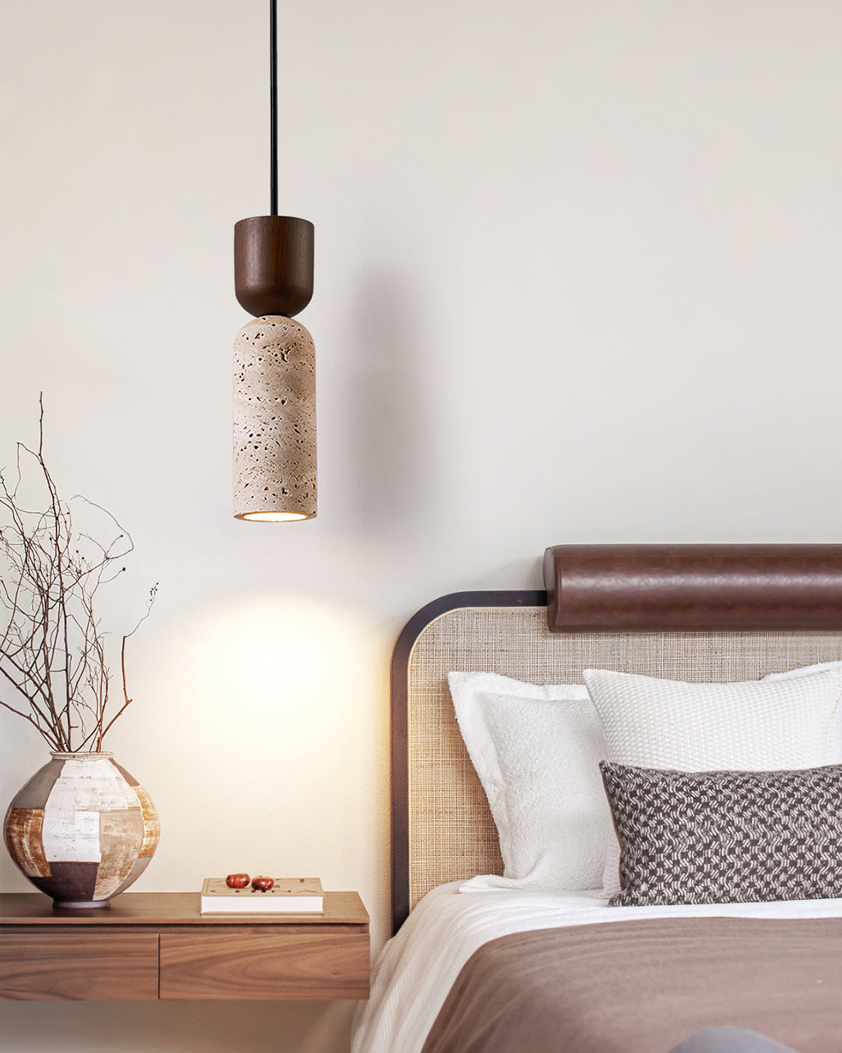 Clérachic pendant with a walnut cap and stone body hanging by a bed with a rattan headboard and a round vase on the nightstand.
