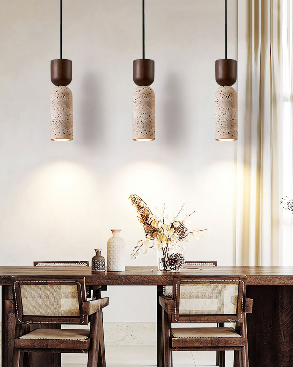 Three Clérachic pendants over a walnut dining table with rattan chairs, each casting a warm cone of light on the wall behind.