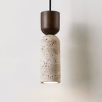 Lit Clérachic travertine pendant with a rounded walnut cap, photographed against a pale grey wall with a soft shadow.