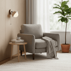 Single travertine dome light on a pale panelled wall, above a grey armchair, a round side table and a potted fig; a Clérachic wall light.