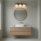 Three-dome Clérachic wall light above a round mirror and a floating oak vanity in a bathroom with pale green panelled walls.