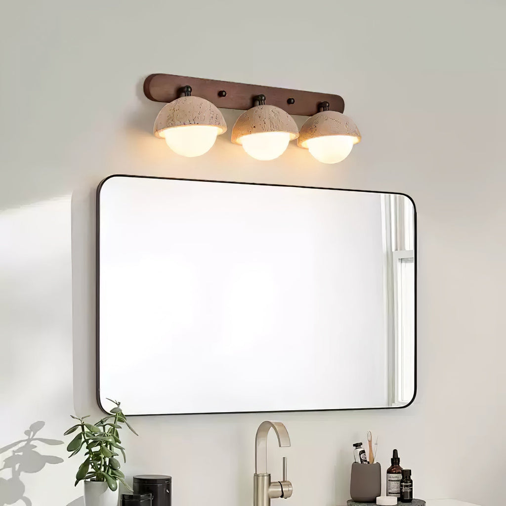 Travertine domes with warm light under them, on a walnut bar above a black-framed mirror; a Clérachic bathroom wall light.