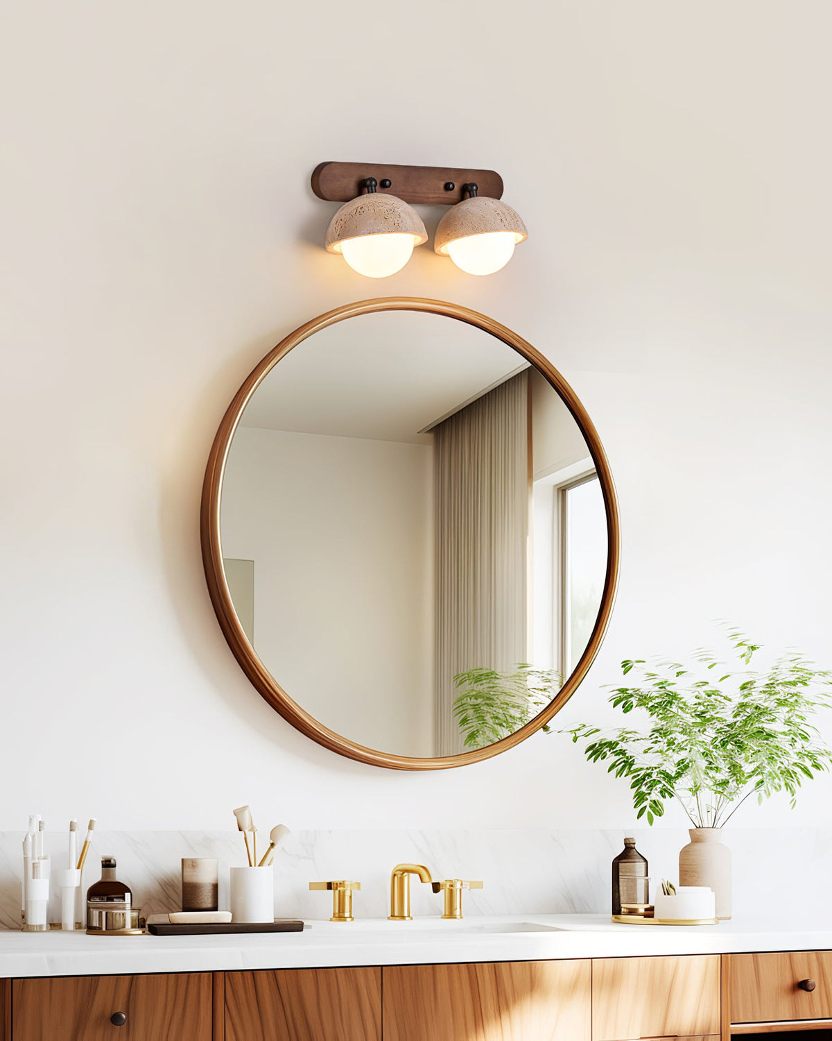Two travertine domes lit on a walnut bar, a Clérachic wall light above a round wood-framed mirror and a vanity with brass taps.