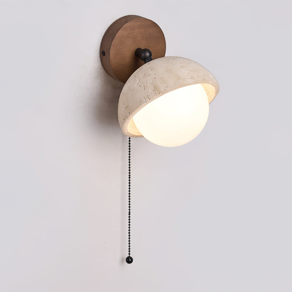 Side view of the travertine dome and white glass globe on this Clérachic wall light, with its walnut round backplate and pull chain.