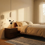 Clérachic's round travertine pendant lights a bedside nightstand, its warm glow falling beside a linen-dressed bed.