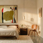 In this bedroom corner, Clérachic's travertine drum pendant hangs beside a wood chair, nightstand and framed art.