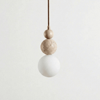 A Clérachic pendant with a travertine top bead and a copper-toned cord fitting above a travertine ball and a white globe.