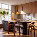 This Clérachic pendant light hangs in a trio above a terrazzo kitchen island with three walnut stools.