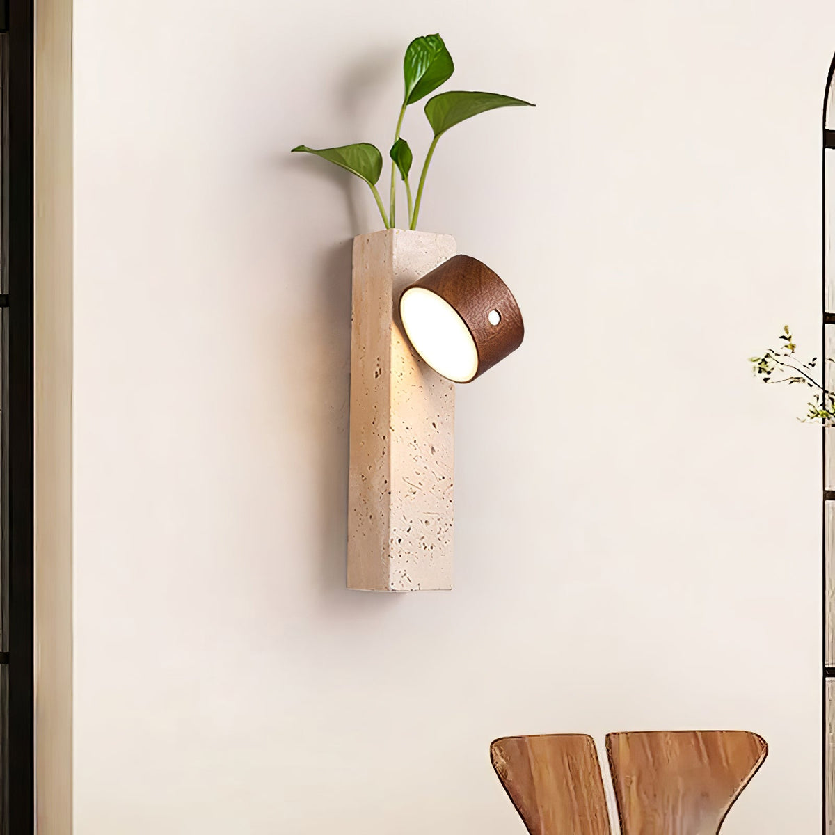 A Clérachic dark walnut wall light on a Yellow Travertine block with a green plant growing from the top, beside an arched window.