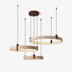 Three travertine rings hang at different heights from a round walnut-toned canopy, each lit from within, on a white backdrop, from Clérachic.
