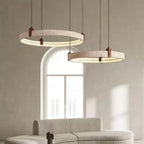 Two of the lit travertine rings on this Clérachic pendant hang in front of an arched window, above the curve of a pale sofa.