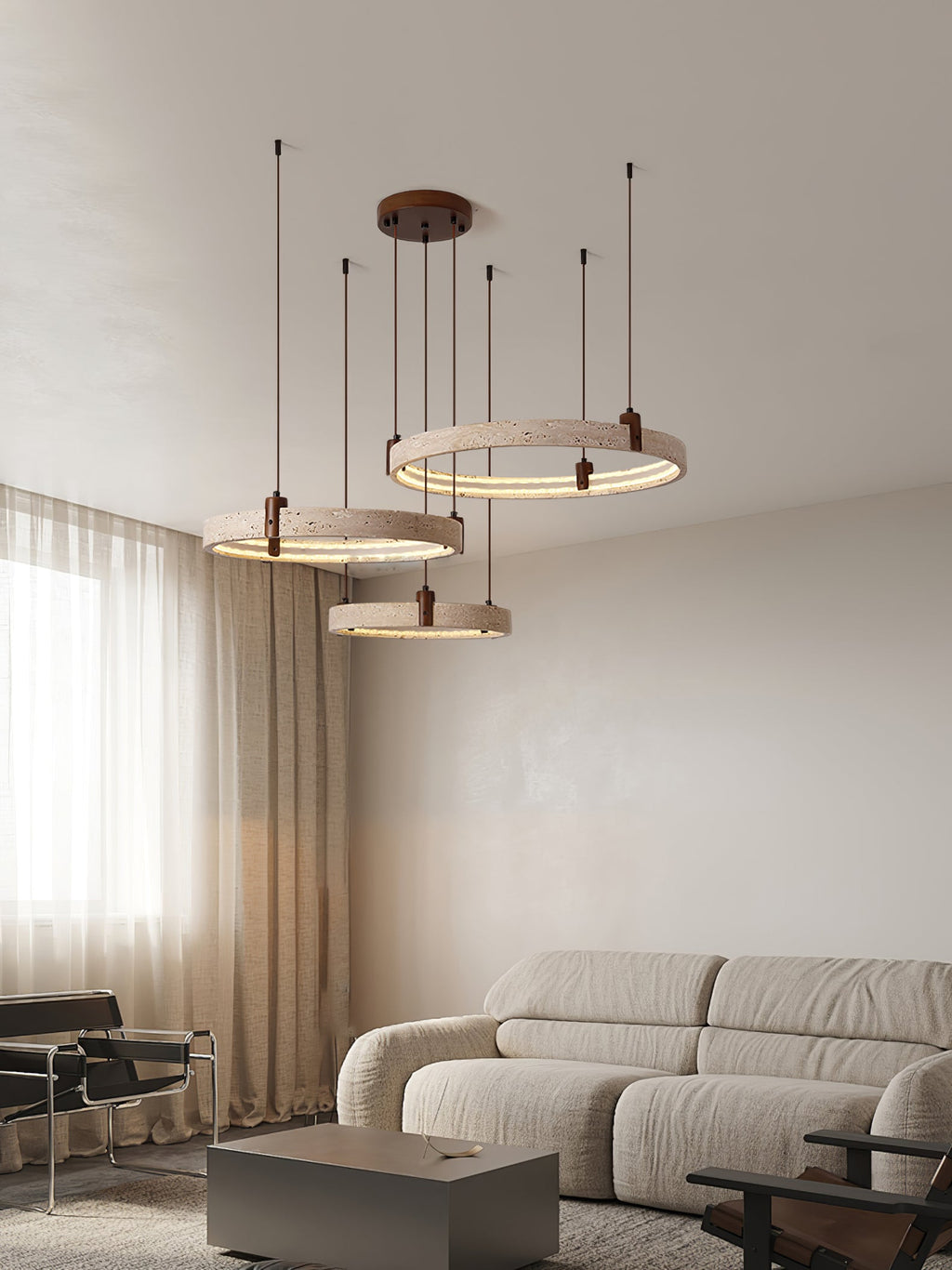 Tall portrait view of this Clérachic travertine ring pendant near a curtained window, above a grey sofa and a low side table.