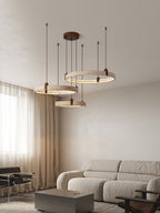 Tall portrait view of this Clérachic travertine ring pendant near a curtained window, above a grey sofa and a low side table.