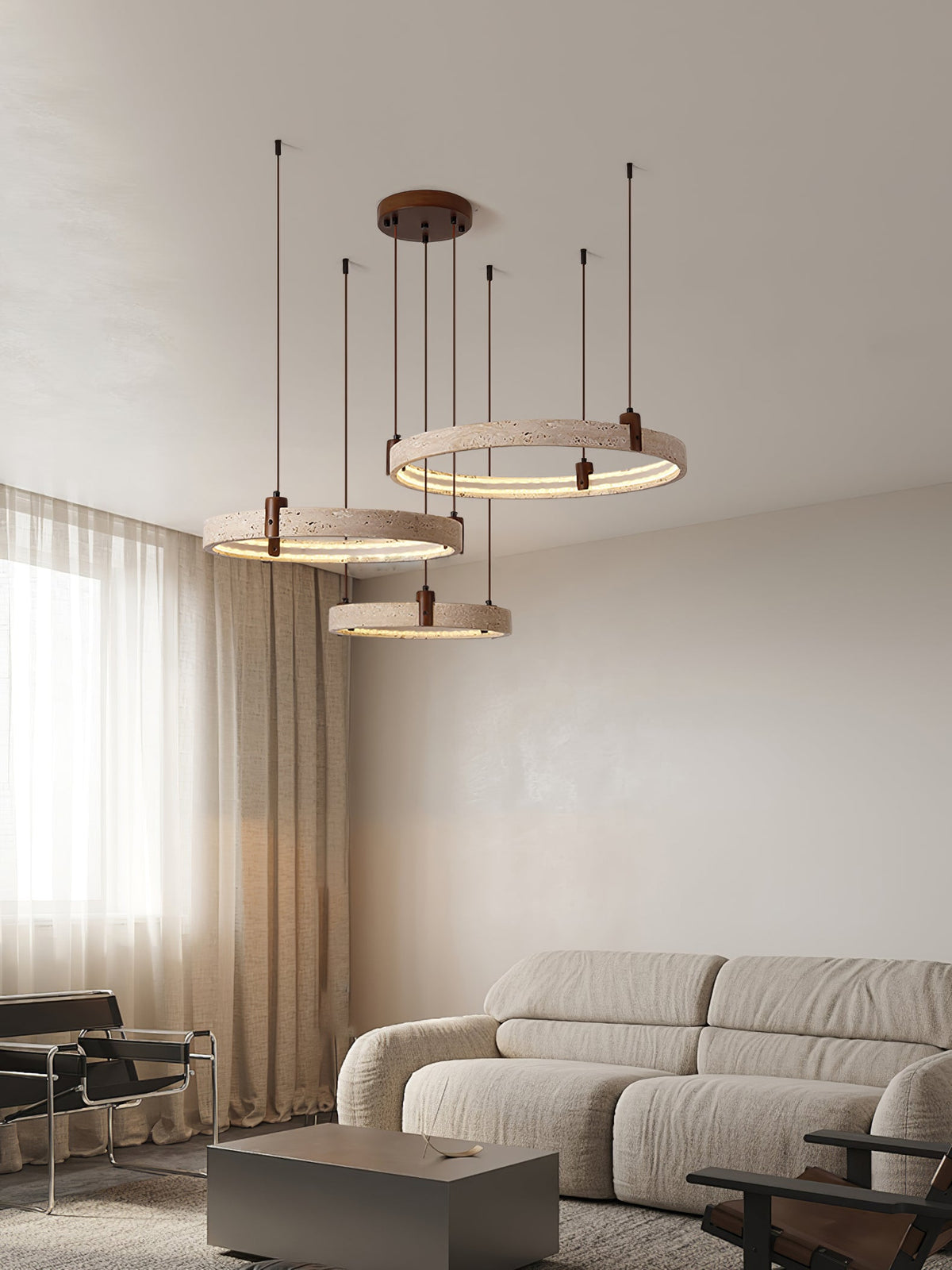 Tall portrait view of this Clérachic travertine ring pendant near a curtained window, above a grey sofa and a low side table.