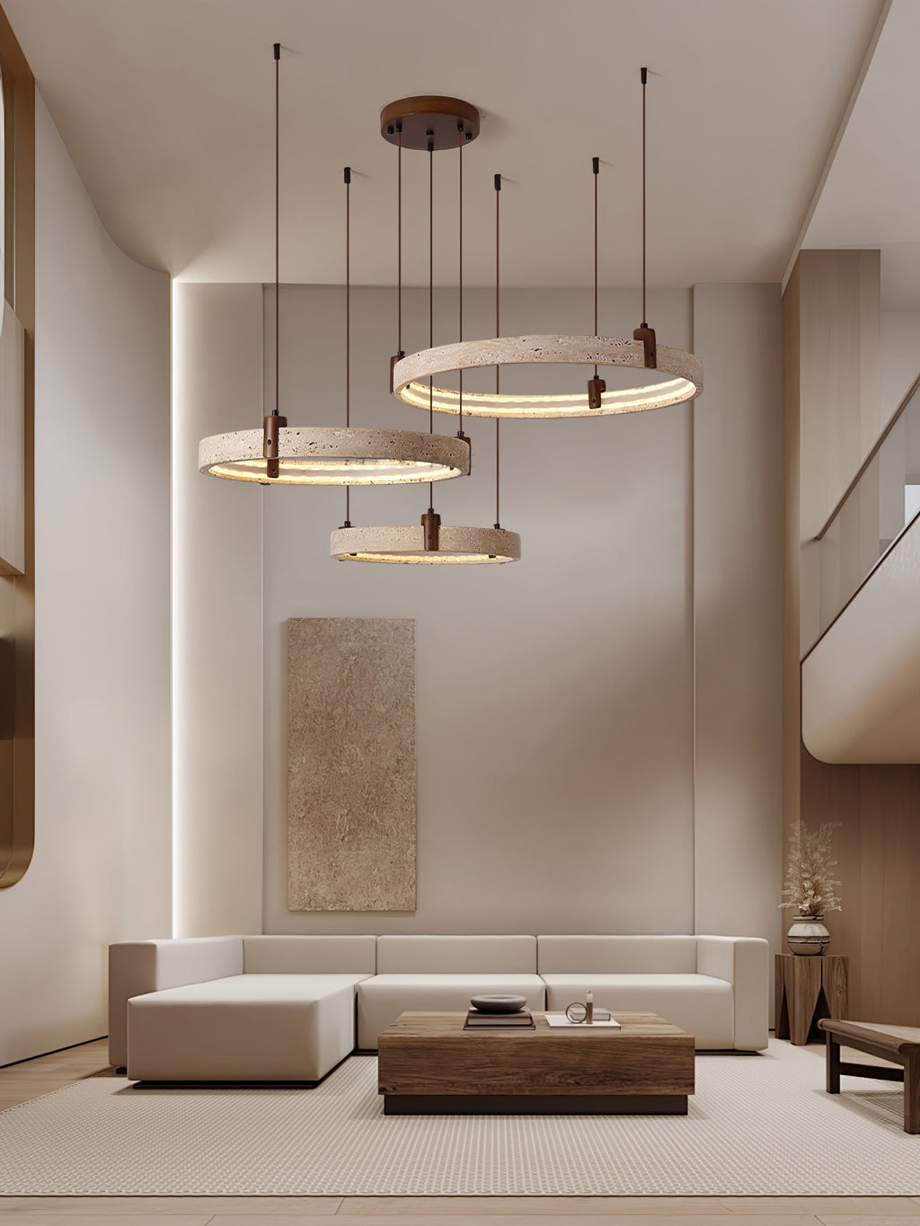 In a tall living room with a stone-toned wall panel and a low timber table, a Clérachic cluster of three travertine rings hangs high.