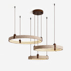 Close view of three lit travertine rings with brown cords and a round walnut-toned canopy on this Clérachic pendant, on white.