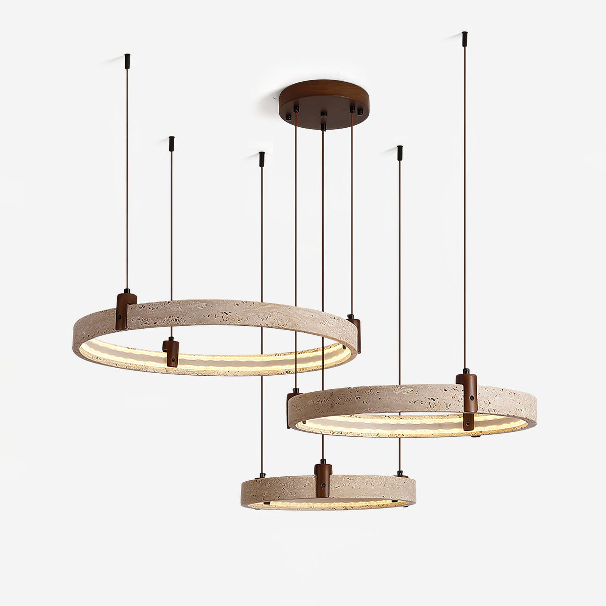Close view of three lit travertine rings with brown cords and a round walnut-toned canopy on this Clérachic pendant, on white.