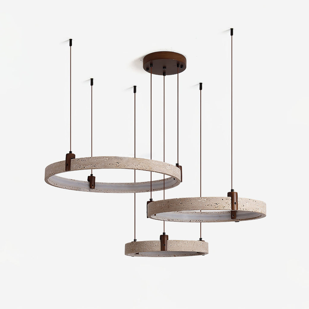 Pitted travertine rings in grey-beige hang on a Clérachic pendant, shown switched off, with their cords rising to a round canopy.
