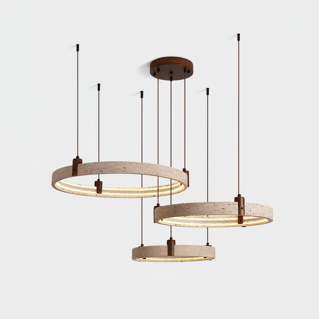 Switched on, the three travertine rings of this Clérachic pendant glow warm along their inner edge, on a pale grey backdrop.