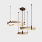 Switched on, the three travertine rings of this Clérachic pendant glow warm along their inner edge, on a pale grey backdrop.