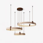 Cords of different lengths hold three glowing travertine rings on this Clérachic pendant, shown on a pale studio backdrop.