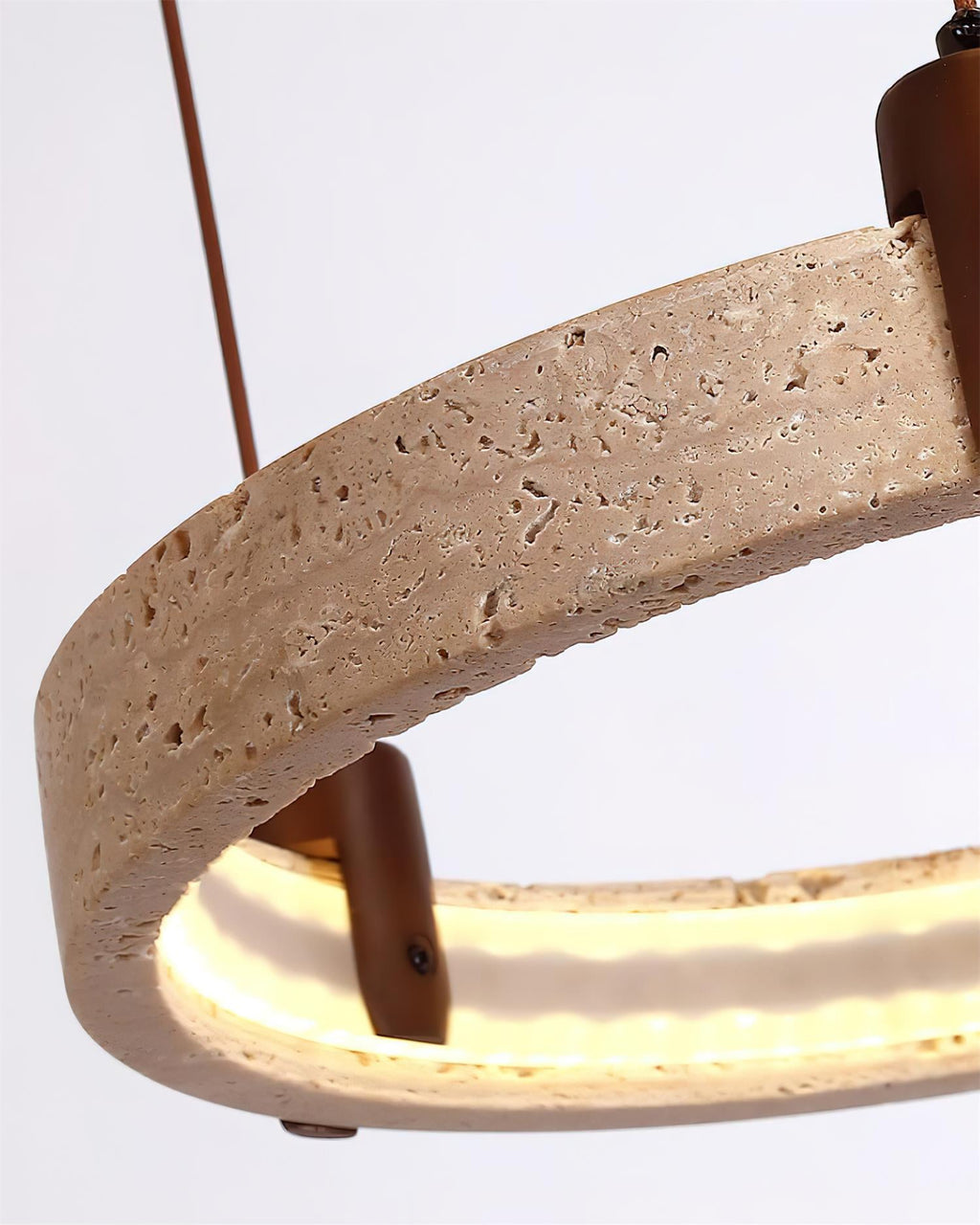 Close view of the pitted travertine surface and a walnut-toned bracket on this Clérachic pendant, with the lit inner edge below.