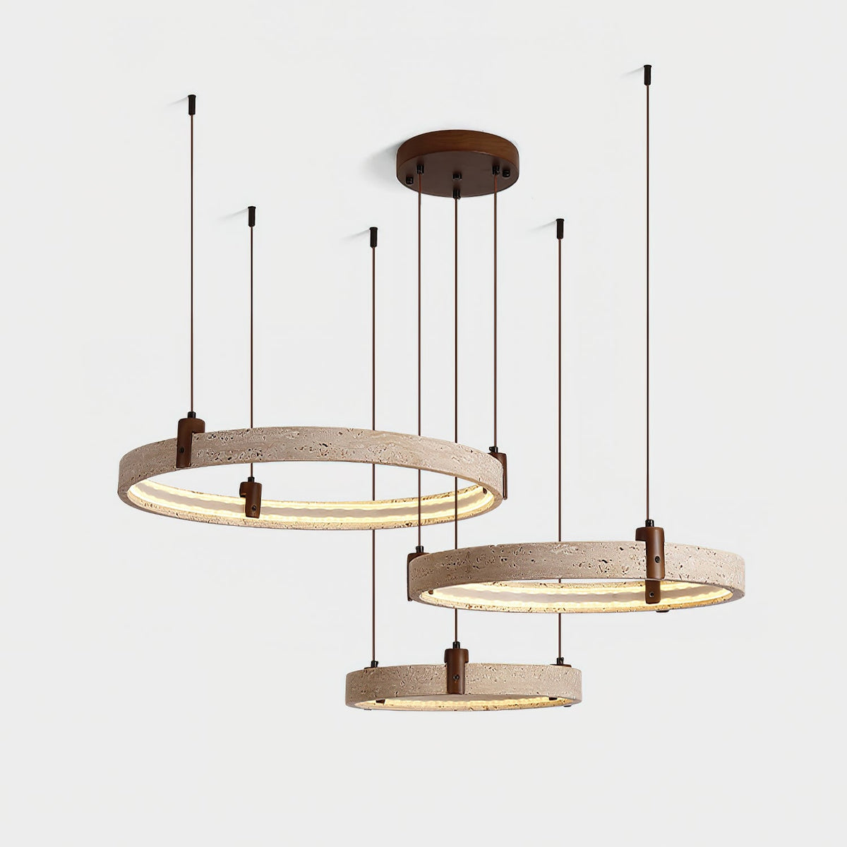 Three lit travertine rings with brown cords on a Clérachic pendant, shown from slightly above on a soft grey backdrop.