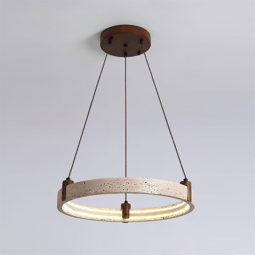 A single Clérachic travertine ring pendant hangs on three angled cords, lit warm inside, against a pale blue-grey backdrop.