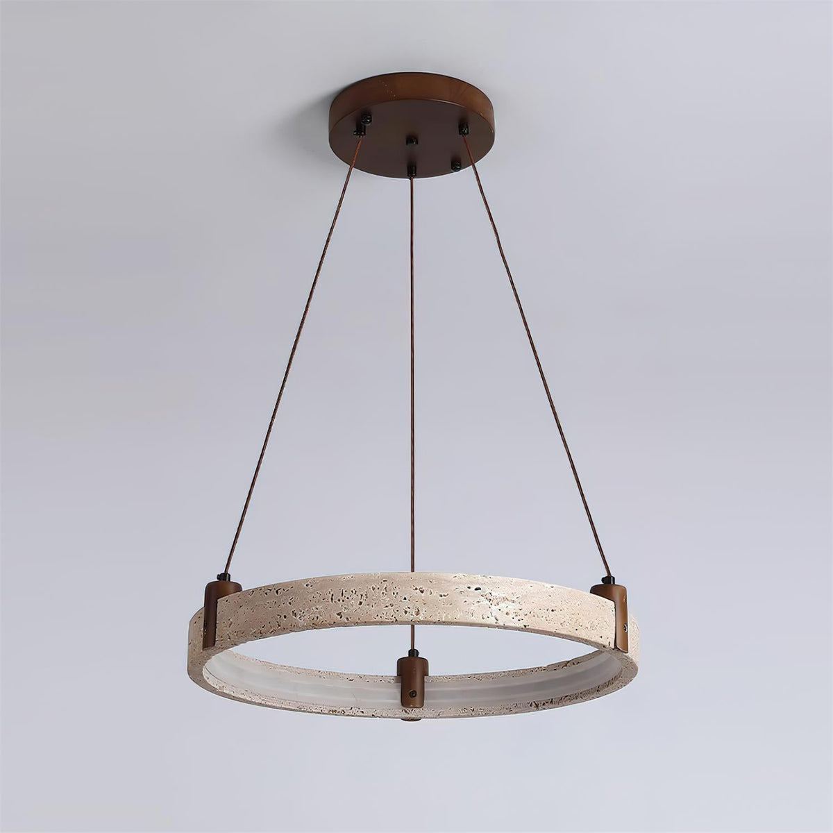 This Clérachic travertine ring pendant is shown switched off, with a pale stone outer face and a grey inner band, on a blue-grey wall.