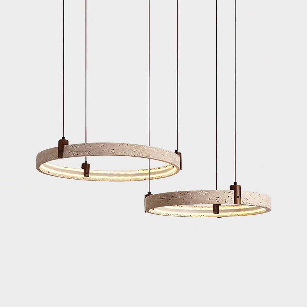 Two lit travertine rings from Clérachic hang on straight cords, one above the other, in front of a pale grey backdrop.