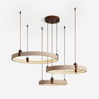 Three travertine rings with warm light inside hang from a round canopy on this Clérachic pendant, shown on an off-white backdrop.