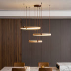 Seen at eye level, a Clérachic pendant of three travertine rings hangs over a marble-topped table and tan leather chairs.