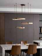 Close view of a golden travertine ring with a walnut bracket and a brown cord on this Clérachic pendant, over dark wood panels.