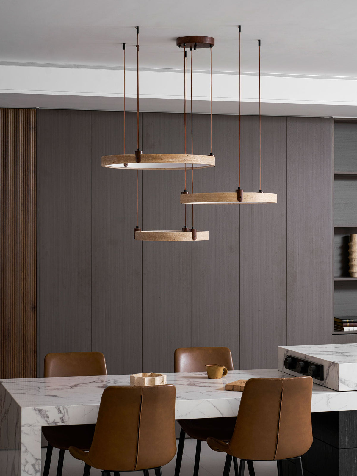 Close view of a golden travertine ring with a walnut bracket and a brown cord on this Clérachic pendant, over dark wood panels.