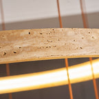 Pitted golden travertine above a glowing band of warm light, shown in close view on this Clérachic ring pendant.