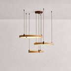 Studio shot of three golden travertine rings on a Clérachic pendant, with the lower ring lit warm, on a soft pink-grey backdrop.