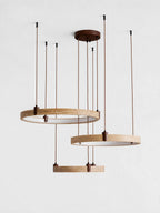 Three travertine rings with white inner faces hang from a round canopy on this Clérachic pendant, against a pale grey backdrop.