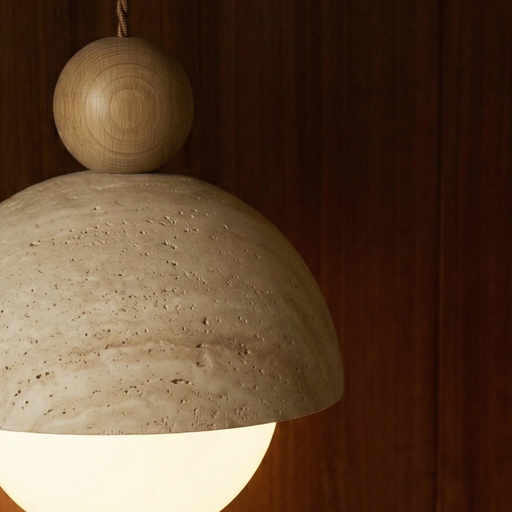 Close-up of the Clérachic pendant light's pale wood ball finial and pitted stone dome shade.