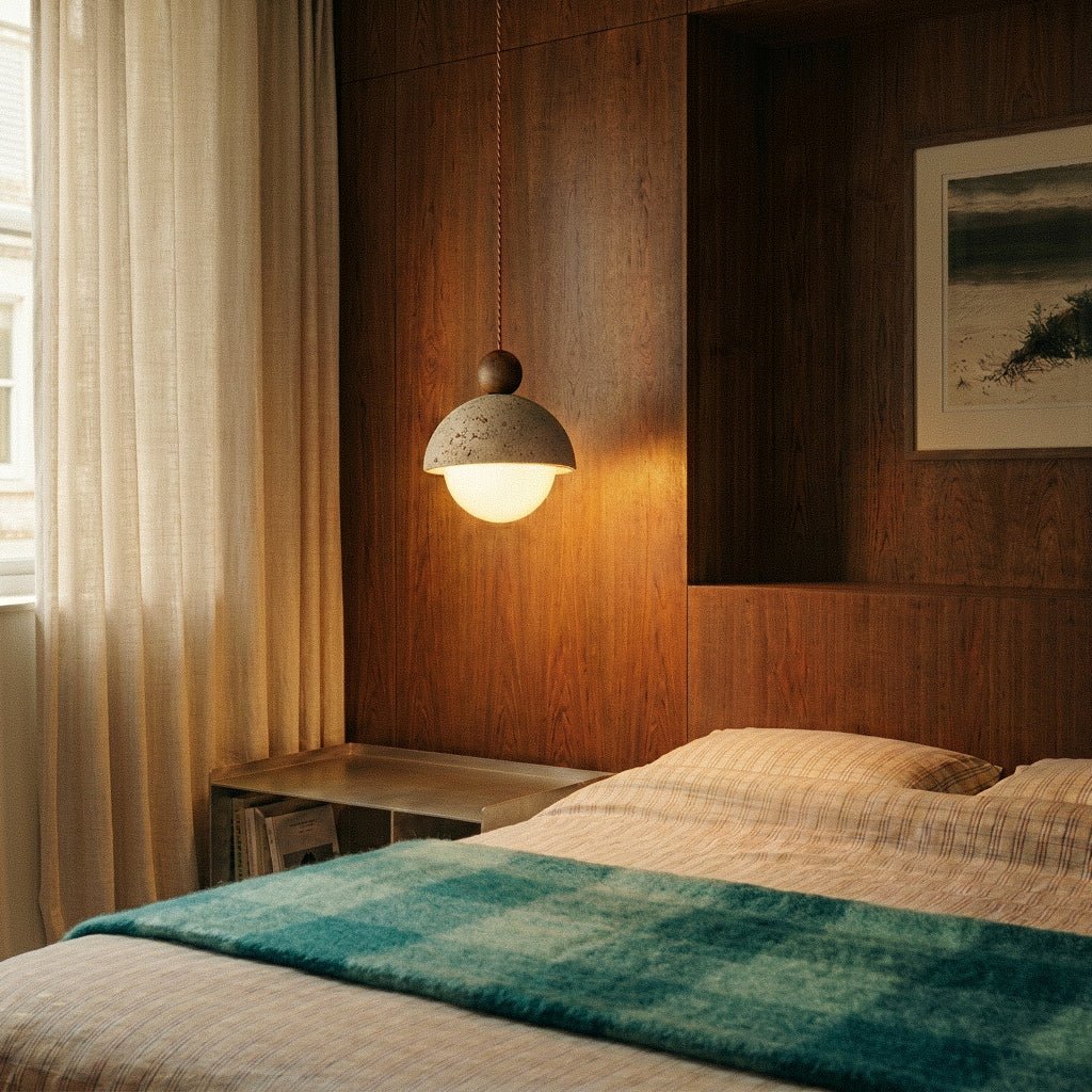 A Clérachic pendant light glows beside a bed with teal plaid linens and wood-panelled walls.