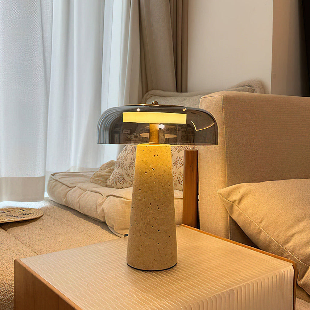 Warm glow from a smoky grey glass dome on this Clérachic lamp, standing on a pale side table next to a cream sofa.