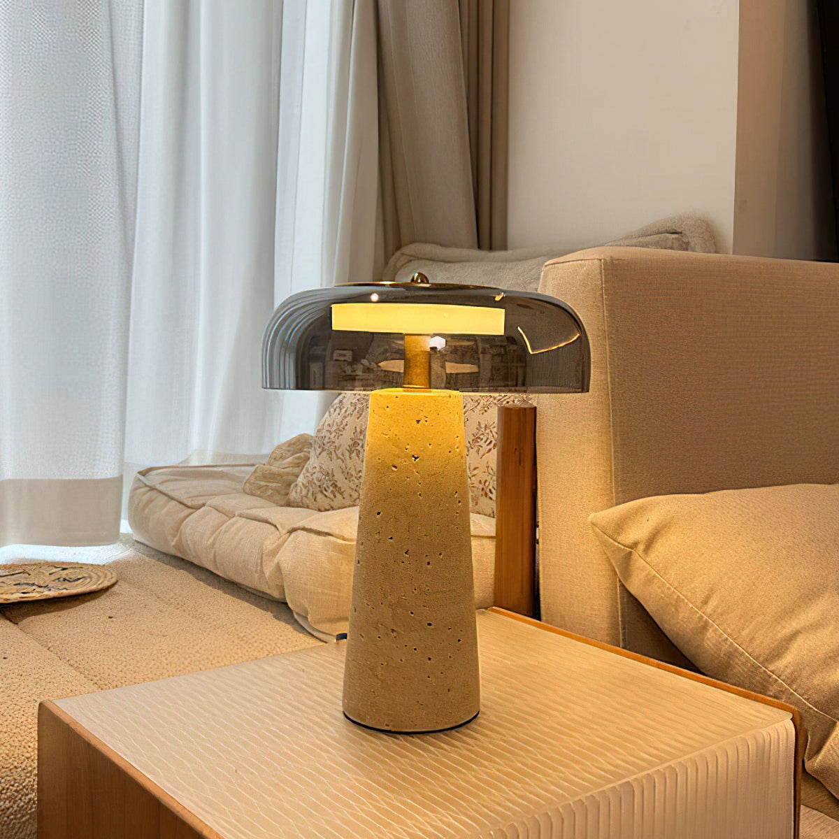 Warm glow from a smoky grey glass dome on this Clérachic lamp, standing on a pale side table next to a cream sofa.