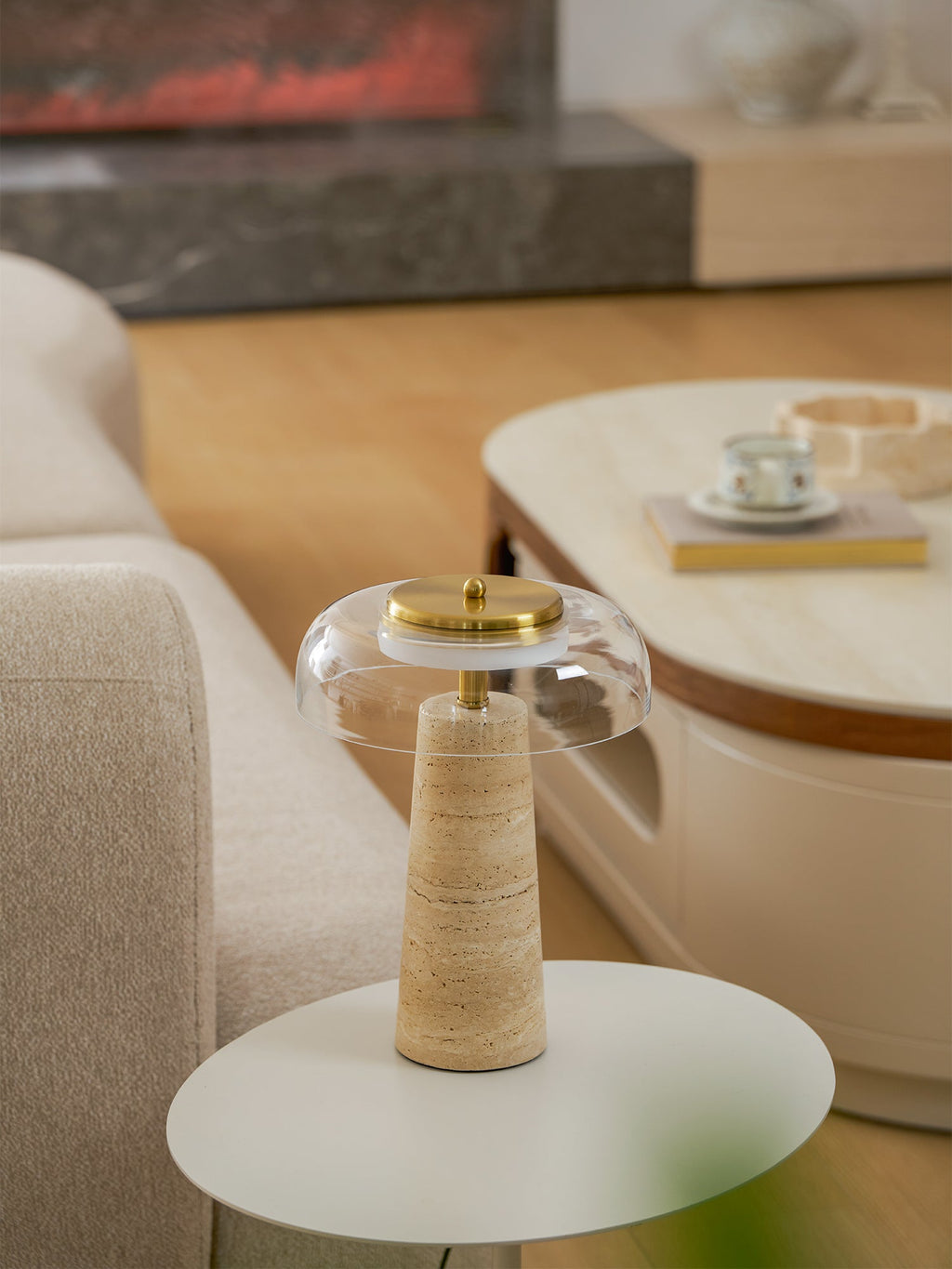Portrait view of this Clérachic table lamp, unlit, on a round white table beside a cream sofa and an oval coffee table with a teacup.