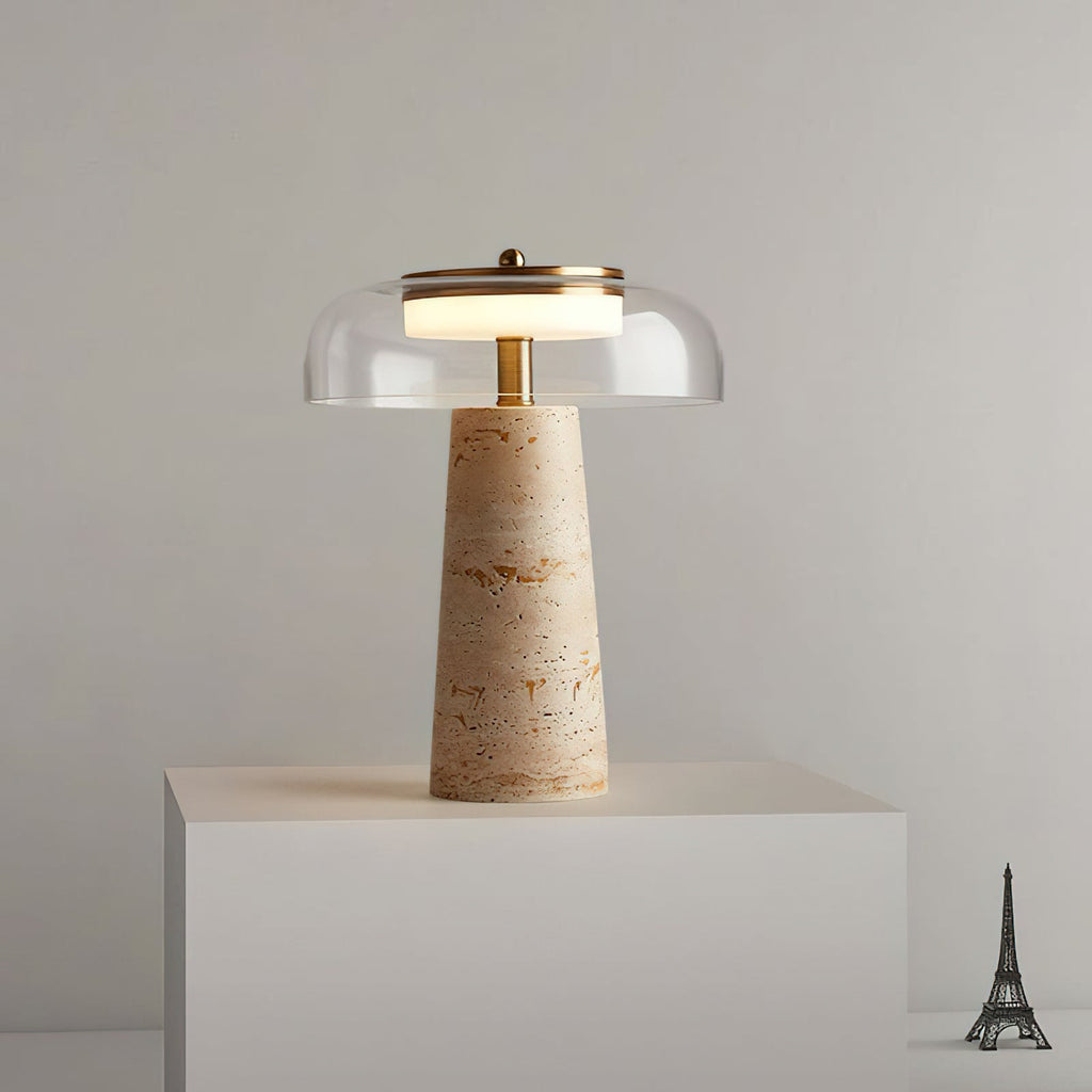 This Clérachic table lamp lit on a white plinth against a grey wall, with a small Eiffel Tower figurine at the right edge.