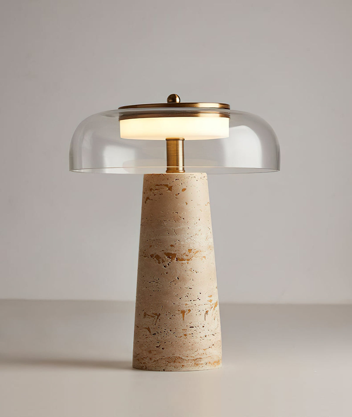 Clear glass dome and brass finial on this Clérachic table lamp, the lit ring of light glowing over a travertine base.